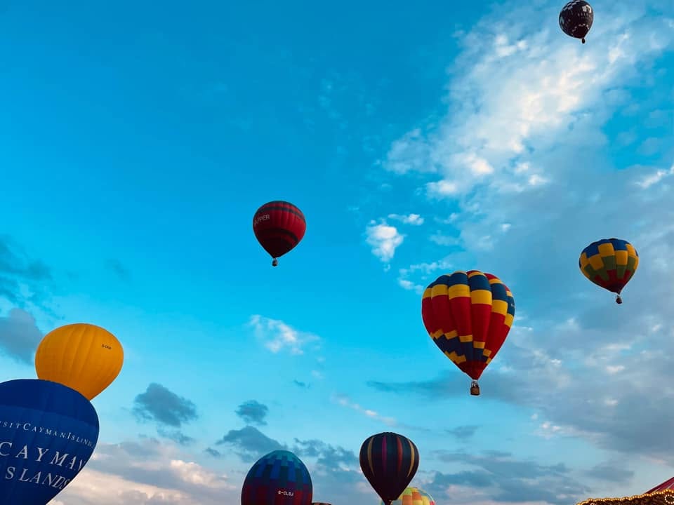 673171166_122181828746606789_7770496465587355584_n - Lydiard Park Multiple colorful hot air balloons floating in a bright blue sky during the day, with clouds visible in the background.